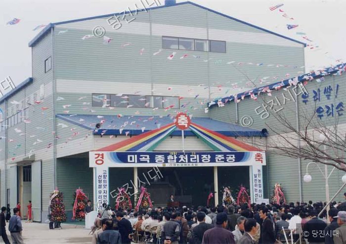 사람들이 모여 미곡종합처리장 준공식을 진행하고 있다.