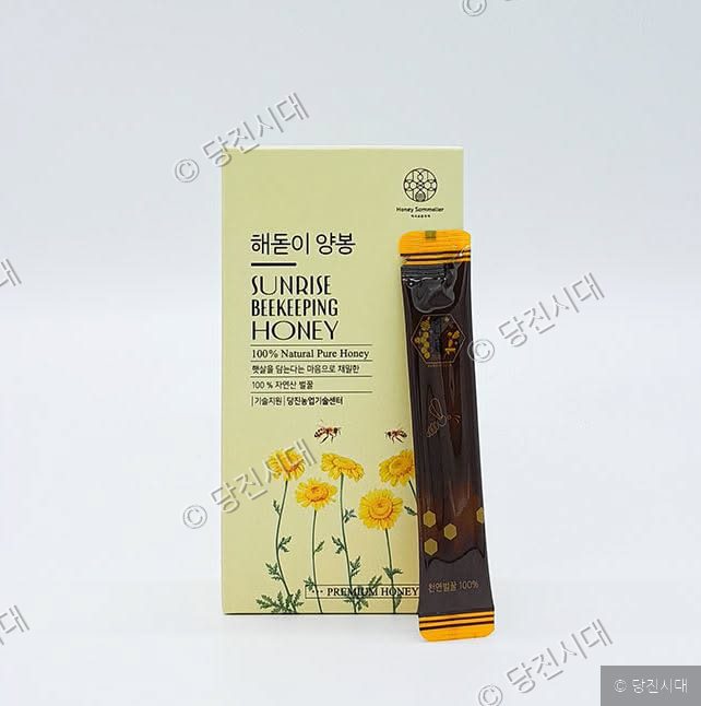 해돋이양봉의 100% 자연산 벌꿀 스틱 제품과 상자가 놓여 있다.