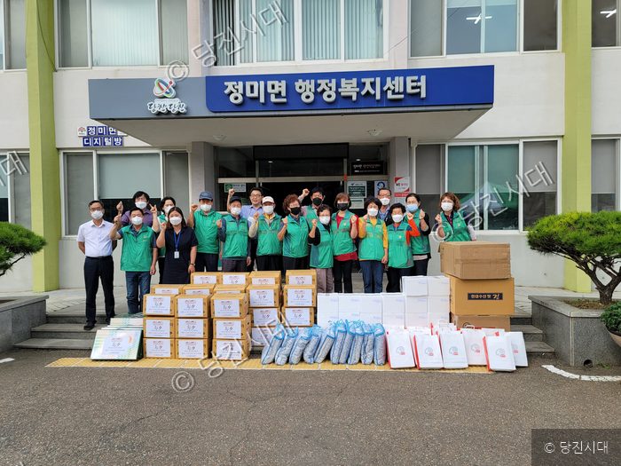 정미면 행정복지센터 앞에서 봉사자들이 나눔 물품을 두고 기념촬영을 하고 있다.