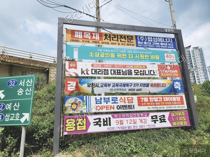 당진시의 한 도로변에 여러 개의 광고 현수막이 걸려 있다.