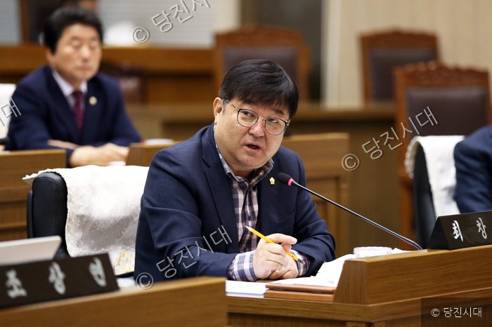 회의실에 앉아 마이크를 잡고 발언하는 남성 의원의 모습