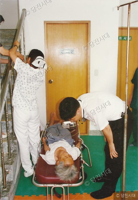 의료진이 환자를 들것에 싣고 이송하고 있다.