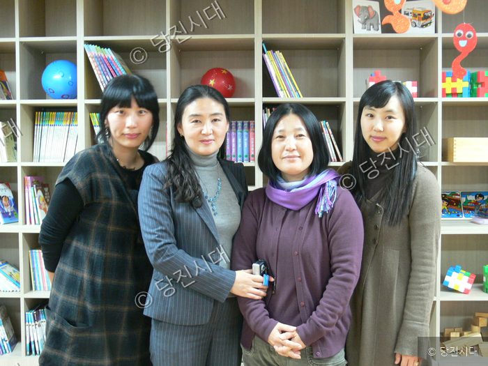 장애인주간보호센터에서 네 명의 여성이 함께 기념 촬영을 하고 있다.