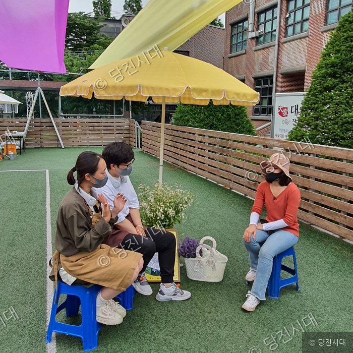 세 청년이 야외에서 대화를 나누고 있다.