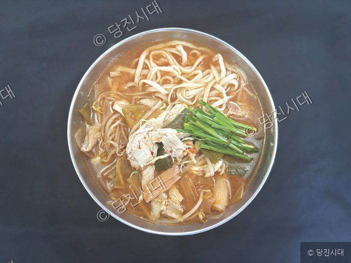 김치와 닭고기가 들어간 닭한마리 칼국수가 그릇에 담겨 있다.