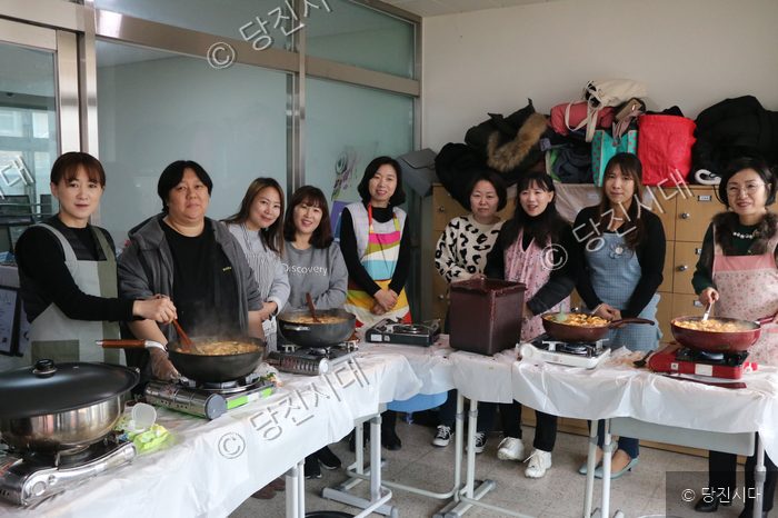 학부모들이 학교에서 요리 활동을 하며 환하게 웃고 있다.