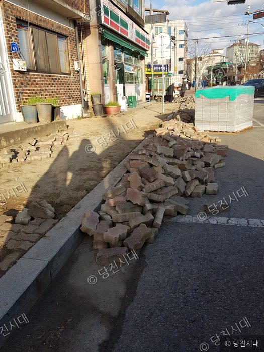 인도에 보도블록 자재와 철거된 블록이 쌓여 있다.