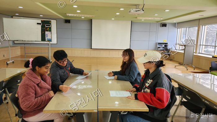 네 명의 교사가 책상에 앉아 자료를 검토하고 있다.