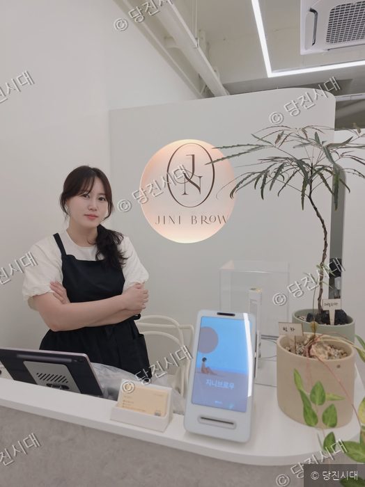 지니브로우의 김희진 대표가 매장 카운터에 서서 포즈를 취하고 있다.