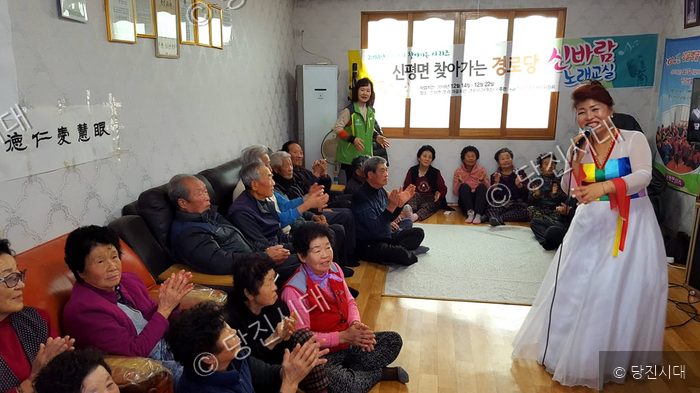 노래교실 강사가 경로당을 찾아와 어르신들 앞에서 노래를 부르고 있다.