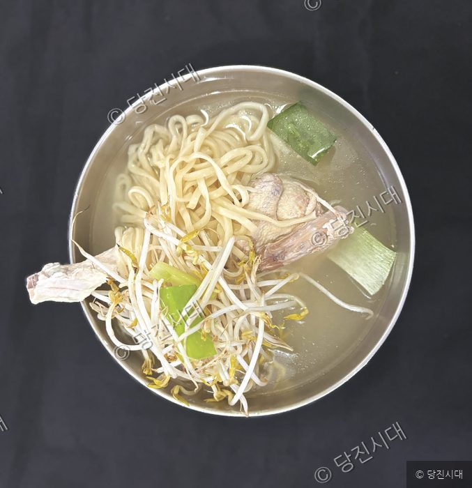 스테인리스 그릇에 담긴 닭한마리 국수가 놓여 있다.