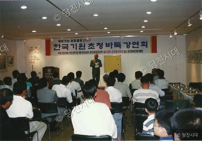 사람들이 강연실에 모여 바둑 강연을 듣고 있다.
