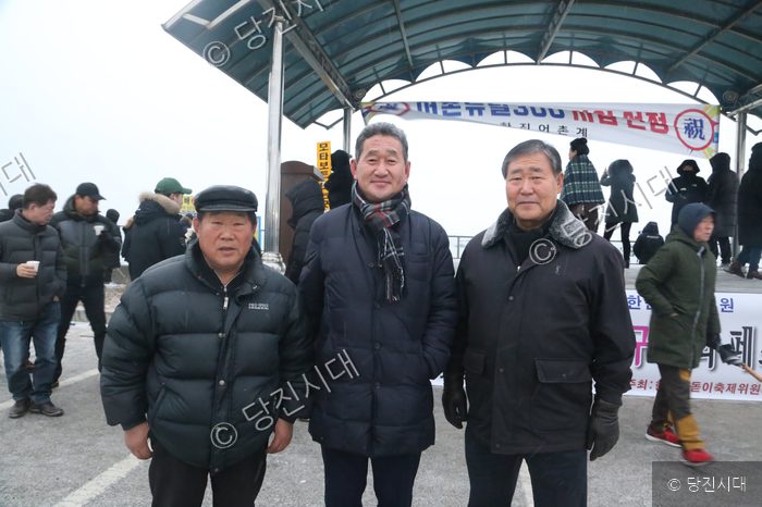 세 명의 남성이 해맞이 행사장에서 기념촬영을 하고 있다.