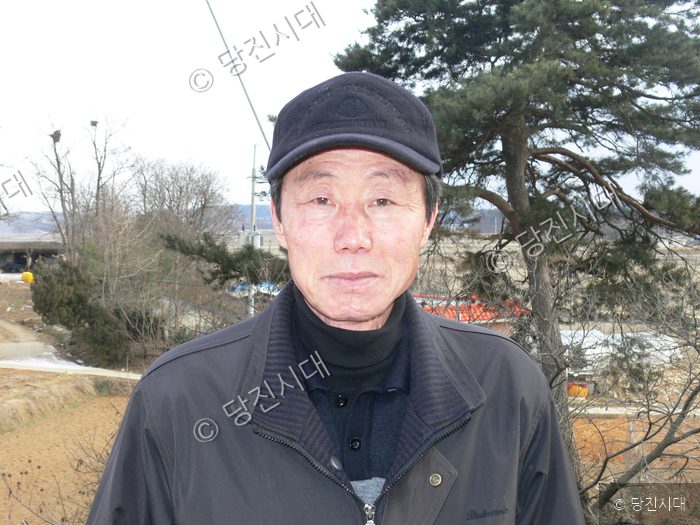김남길 씨가 야외에서 카메라를 향해 미소 짓고 있다.
