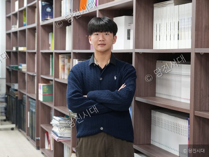 안진성 청주대학교 학생이 서가 앞에서 팔짱을 끼고 포즈를 취하고 있다.