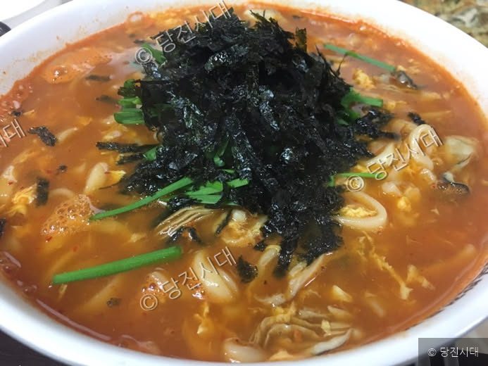 얼큰한 국물의 굴칼국수 위에 김가루와 부추가 올려져 있다.