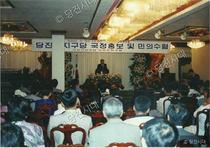 실내 강연장에서 사람들이 모여 행사를 관람하고 있다.