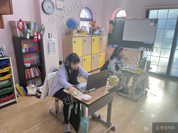두 명의 학생이 교실에서 노트북을 이용해 학습하고 있다.