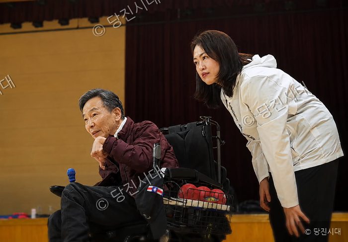 휠체어를 탄 남성과 안지은 대표가 실내에서 이야기를 나누고 있다.
