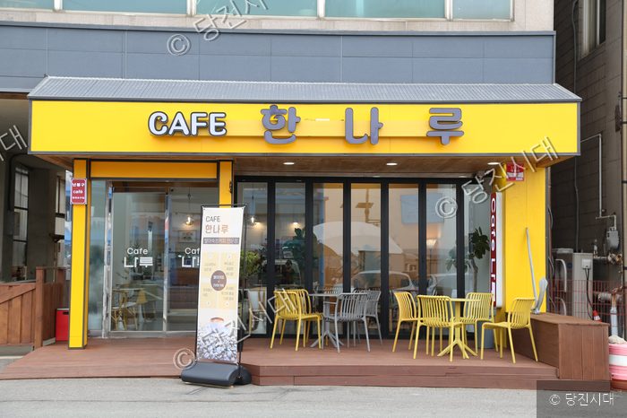 노란색 간판과 테라스가 있는 한나루카페의 외부 모습이다.