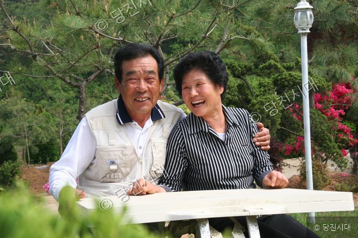 야외 정원에서 중년 부부가 다정하게 웃고 있다.