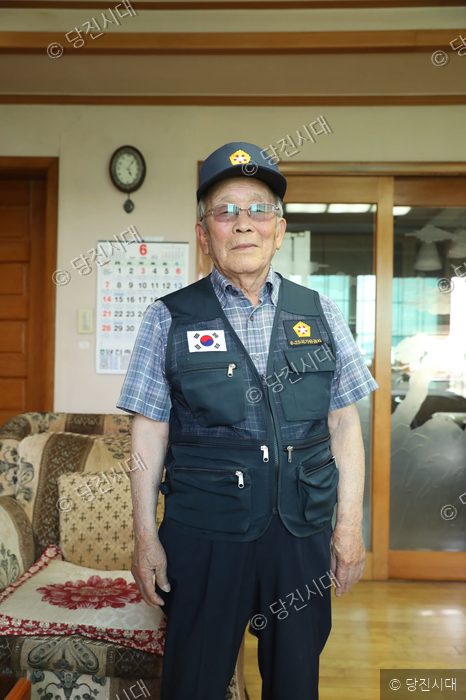 박윤식 옹이 태극기가 부착된 조끼를 입고 서 있다.