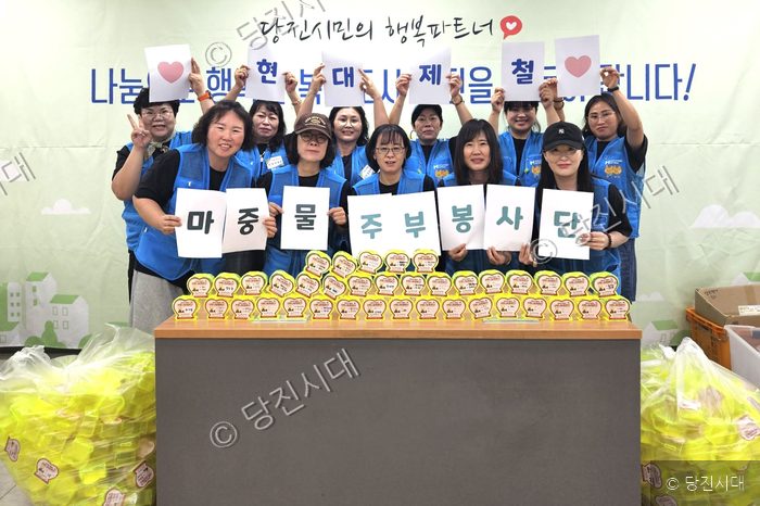 마중물 주부봉사단원들이 봉사활동을 마치고 글자가 적힌 종이를 들어 보이고 있다.