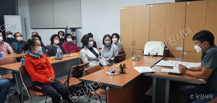 주민들이 회의실에 모여 마을 관계자의 설명을 듣고 있다.