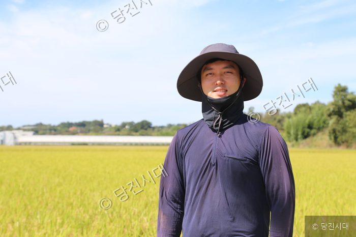 청년농부 김범수 씨가 논을 배경으로 미소를 짓고 있다.