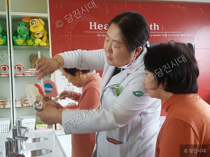 치과 의사가 어르신에게 구강 관리 방법을 교육하고 있다.