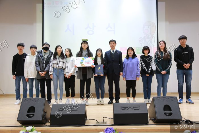청소년들이 무대 위에서 시상식을 진행하며 기념 촬영을 하고 있다.