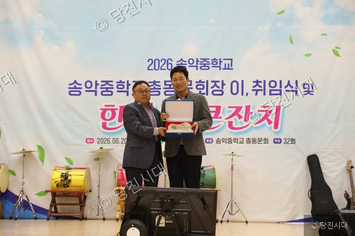 송악중학교 총동문회장 이취임식에서 두 남성이 기념패를 들고 포즈를 취하고 있다.