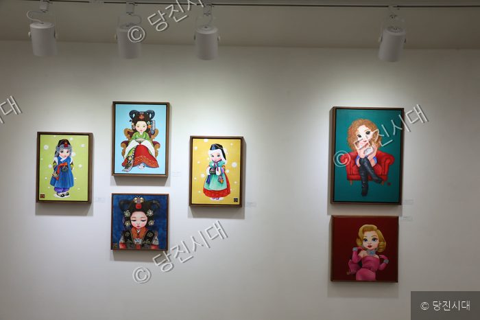 갤러리 벽면에 다양한 베이비돌 인물화가 전시되어 있다.