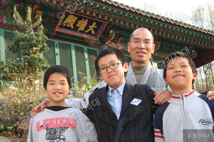 대성사 보각스님과 삼형제가 밝은 미소로 포즈를 취하고 있다.