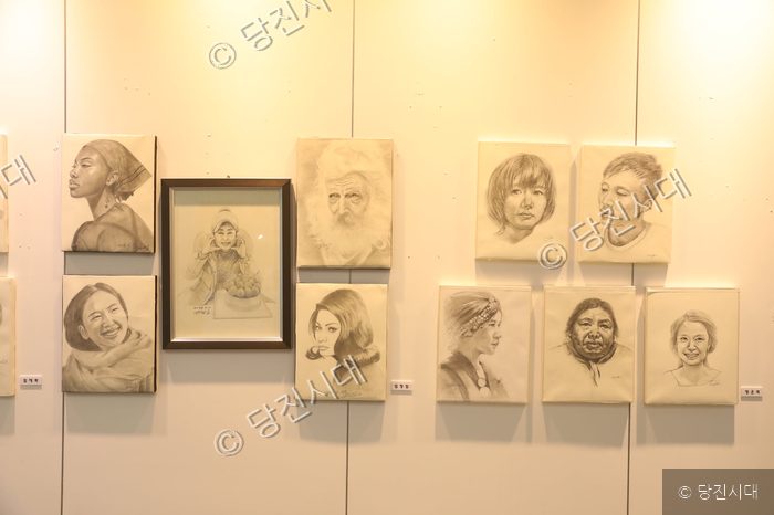 갤러리 벽면에 다양한 인물을 묘사한 연필 초상화 작품들이 걸려 있다.