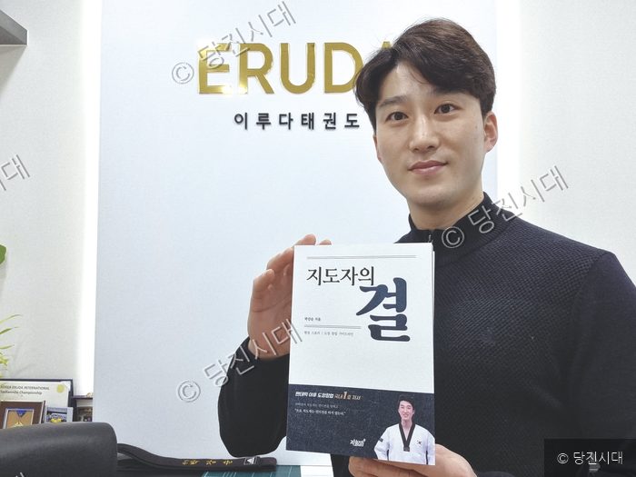 도장 창업 관련 도서를 출간한 관장이 책을 들어 보이고 있다.