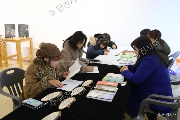 주민들이 책상에 앉아 책에 서명을 하거나 글을 쓰고 있다.