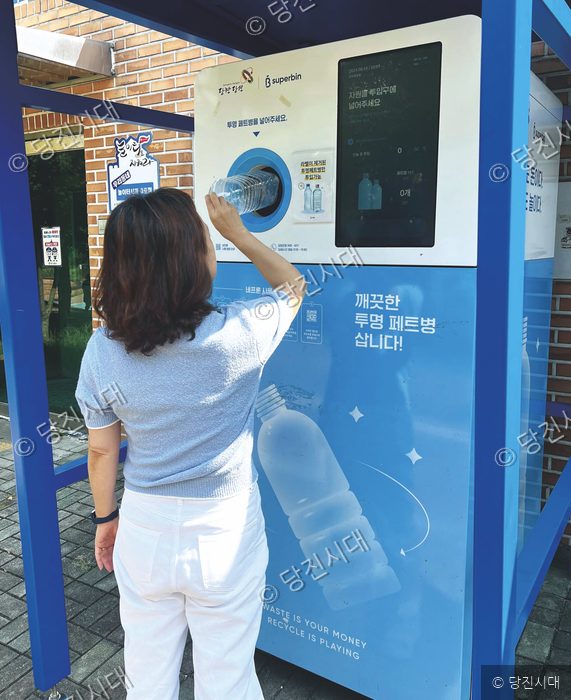 한 시민이 투명 페트병 무인 회수기에 페트병을 넣고 있다.