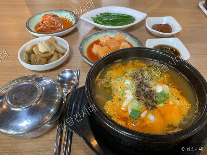 식당 테이블에 소머리국밥과 다양한 밑반찬이 차려져 있다.