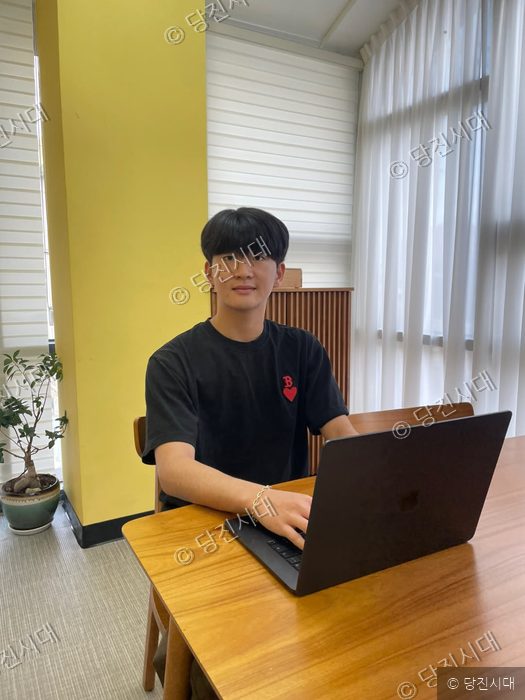 안진성 학생이 노트북 앞에 앉아 포즈를 취하고 있다.