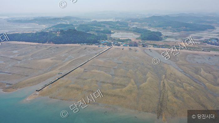 썰물로 드러난 충남 당진의 용무치항 갯벌과 긴 방파제가 내려다보인다.