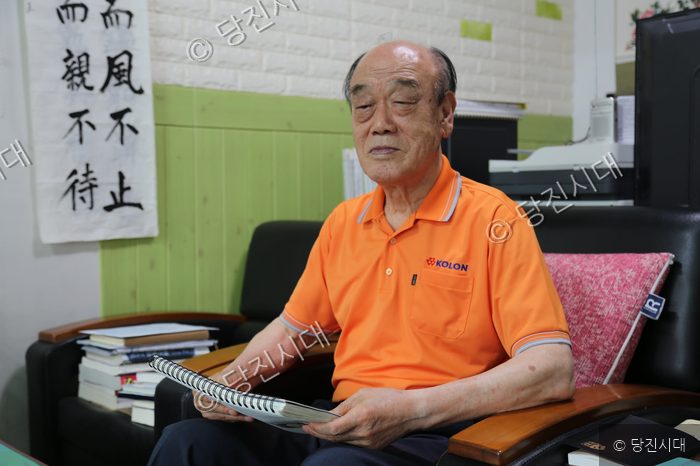 김익진 씨가 의자에 앉아 책을 보고 있다.
