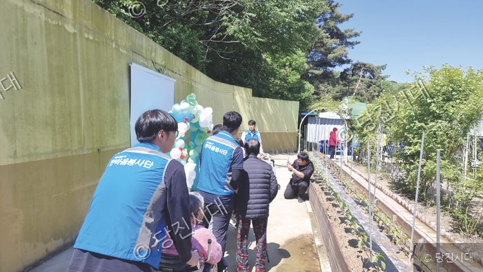 봉사자들이 야외에서 어르신들과 함께 어버이날 봉사활동을 하고 있다.