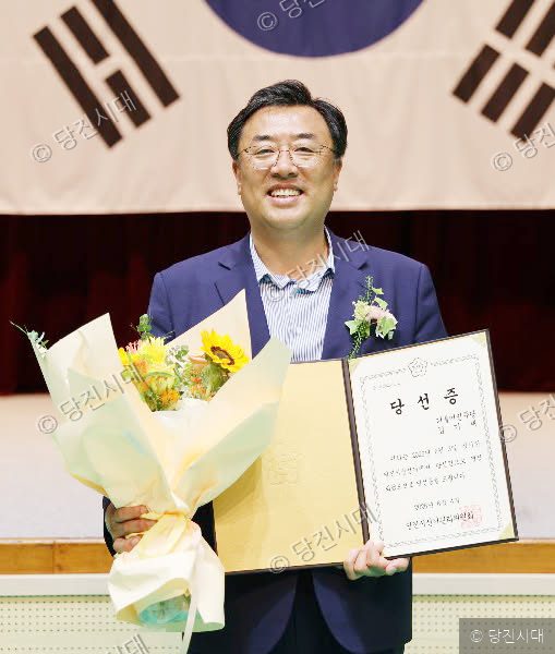 당선증과 꽃다발을 들고 미소 짓는 남성의 모습