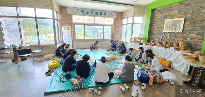 주민들이 실내에서 모여 앉아 짚풀공예를 배우고 있다.