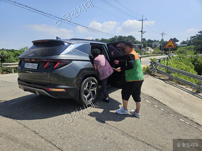 송악읍 자율방재단원이 어르신의 차량 탑승을 돕고 있다.