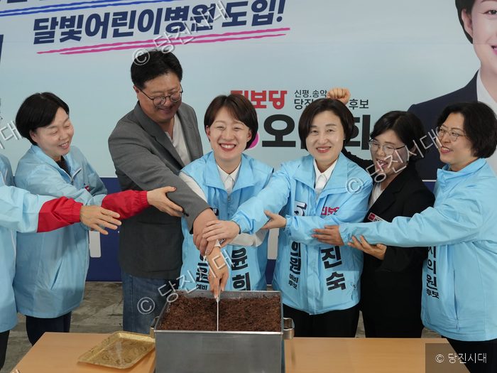 후보들과 지지자들이 선거사무소 개소식에서 시루떡을 자르고 있다.