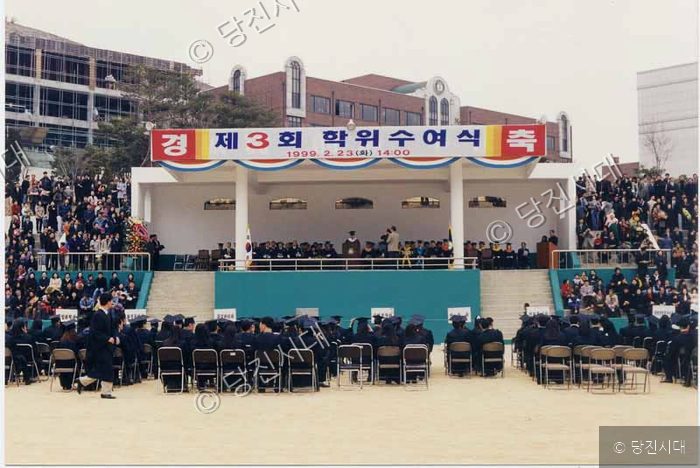 야외 무대에서 대학교 졸업식 학위수여식이 열리고 있다.