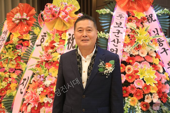 정수영 회장이 축하 화환을 배경으로 서 있다.