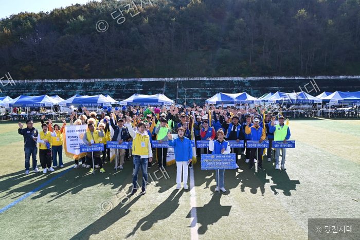 로타리클럽 회원들이 운동장에 모여 기념 촬영을 하고 있다.
